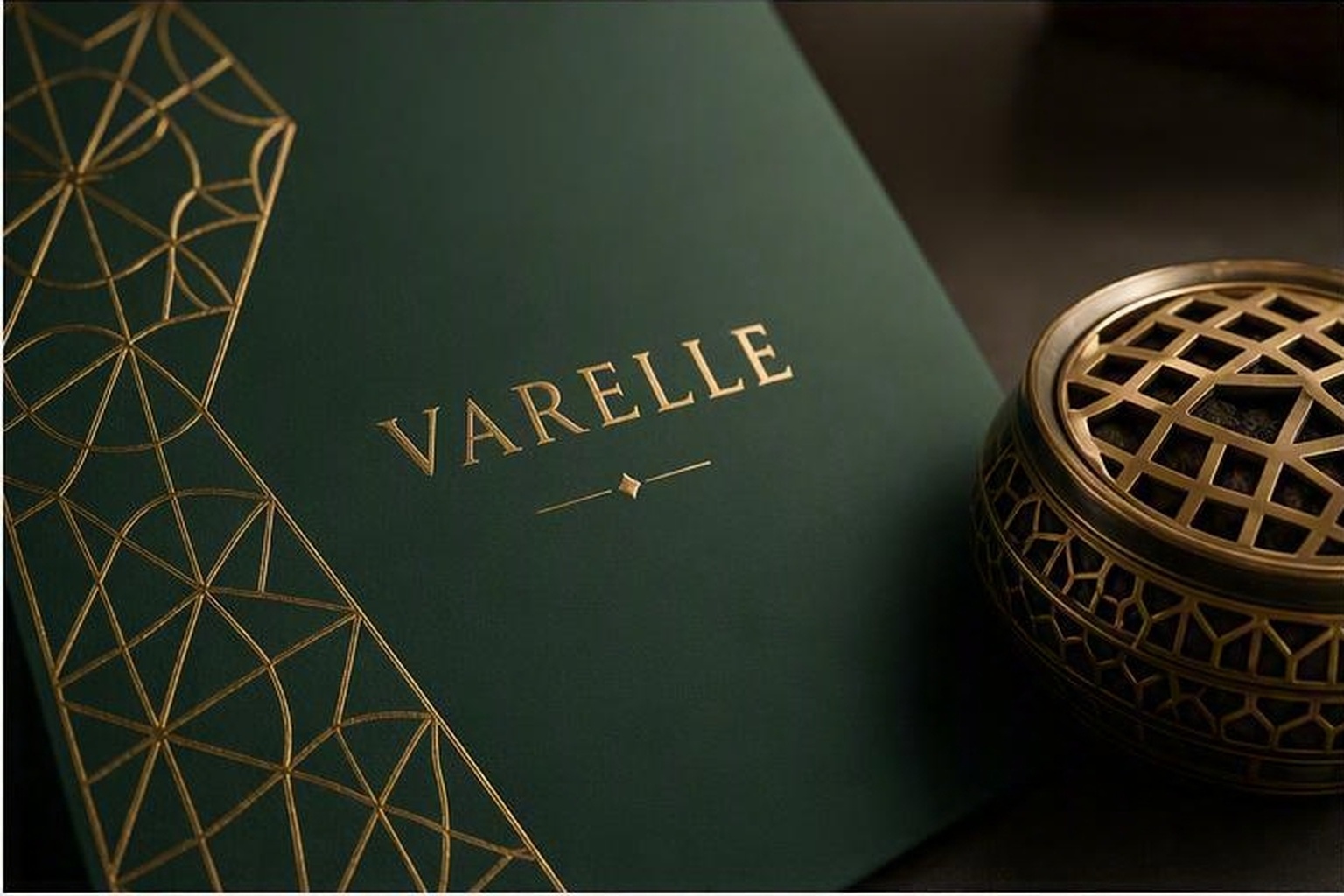 Close-up detail of emerald paperboard with precision gold geometric foil stamping and incense burner